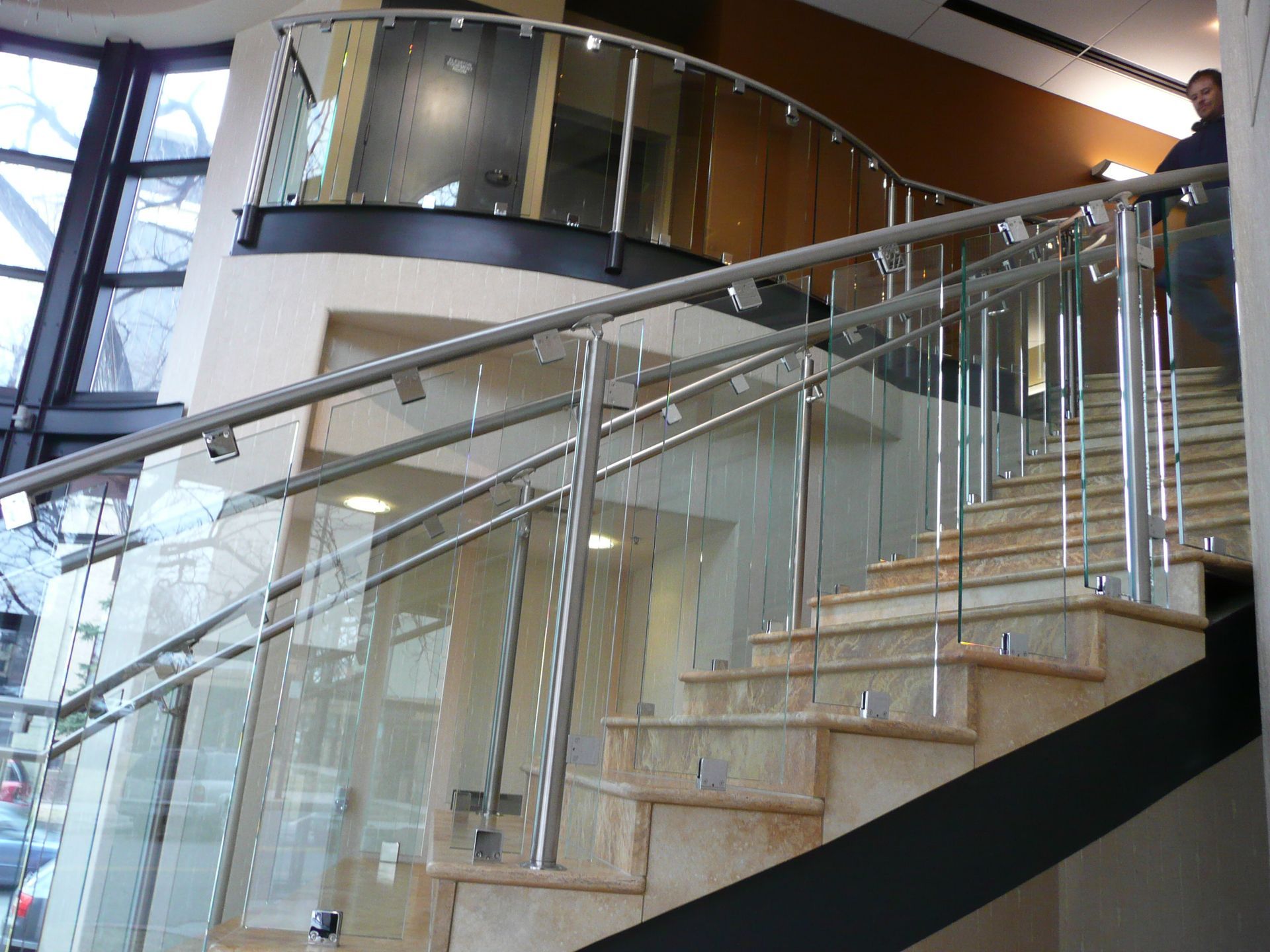 Modern indoor staircase with glass railings and stone steps in a bright atrium