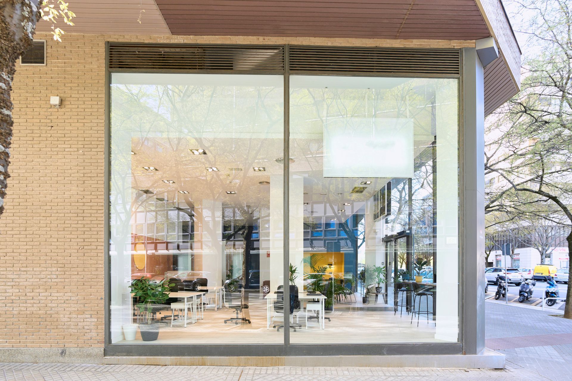 Front view of glass-walled building exterior with empty offices, highlighting glass repair and maintenance services. Storefront with large glass windows, warm interior lighting, and a sidewalk view of the street outside