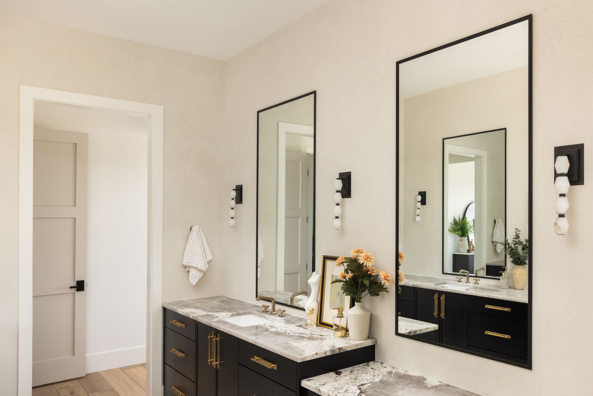 Modern bathroom vanity with double mirrors, dark cabinets, and a white countertop