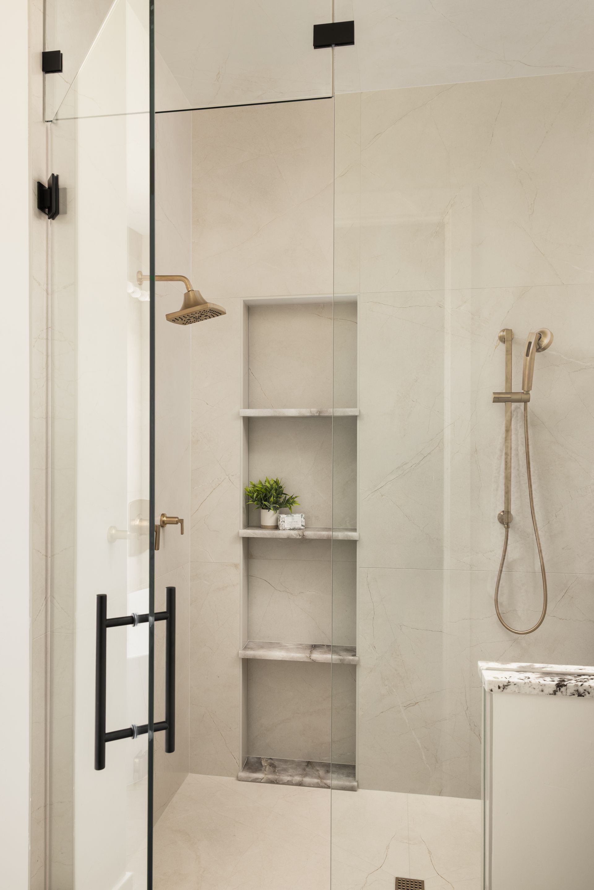 Frameless custom shower door with gray tile walls and modern fixtures