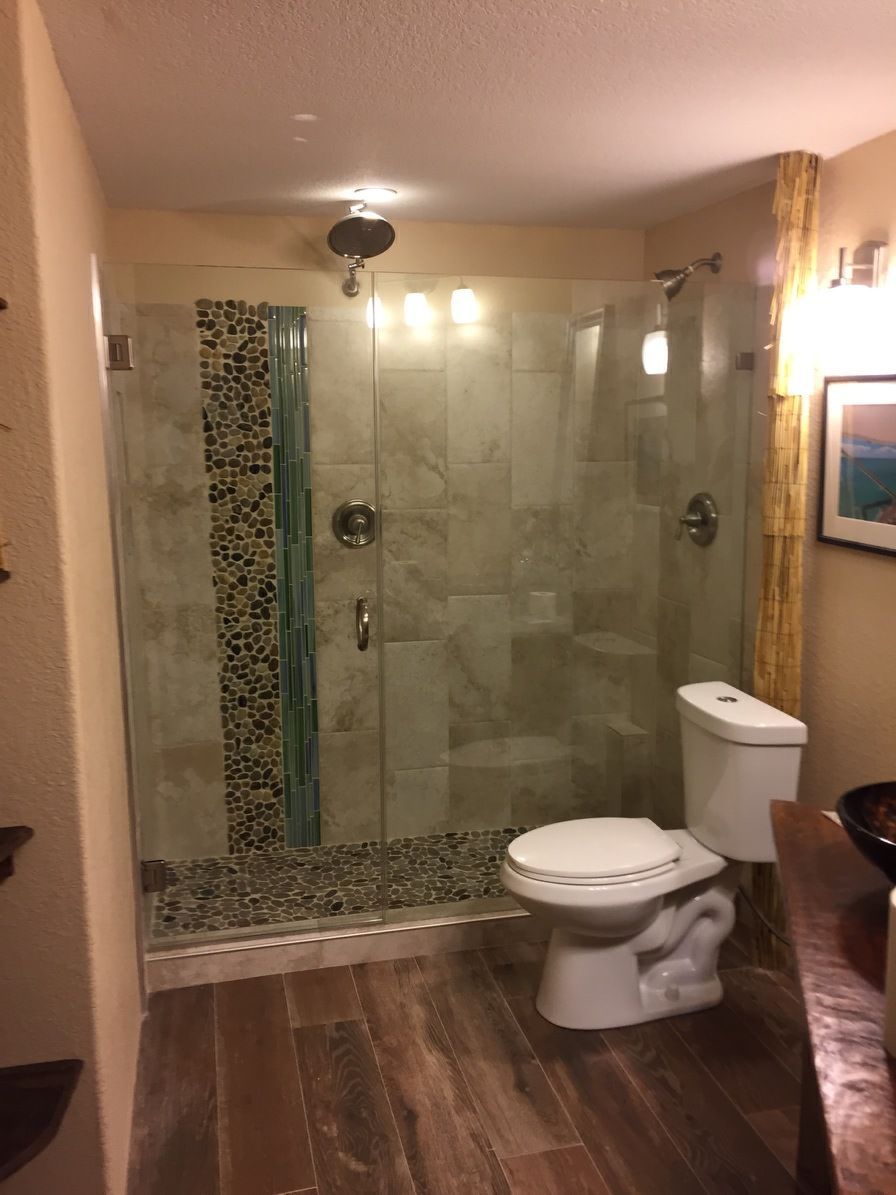 Bathroom with glass walk-in shower, toilet, wood floor, and warm wall lighting