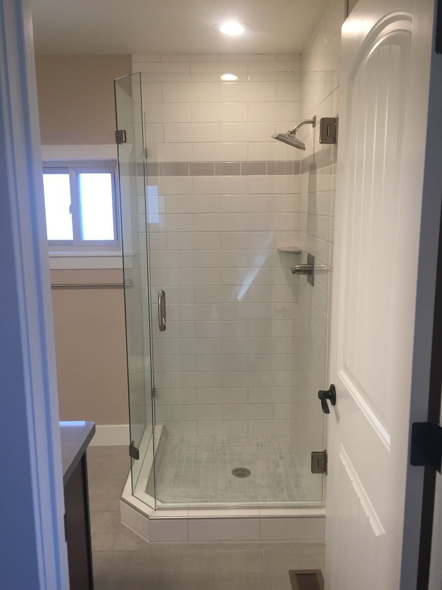 Bathroom with glass walk-in shower, white tile, and tiled step-up base near a window.