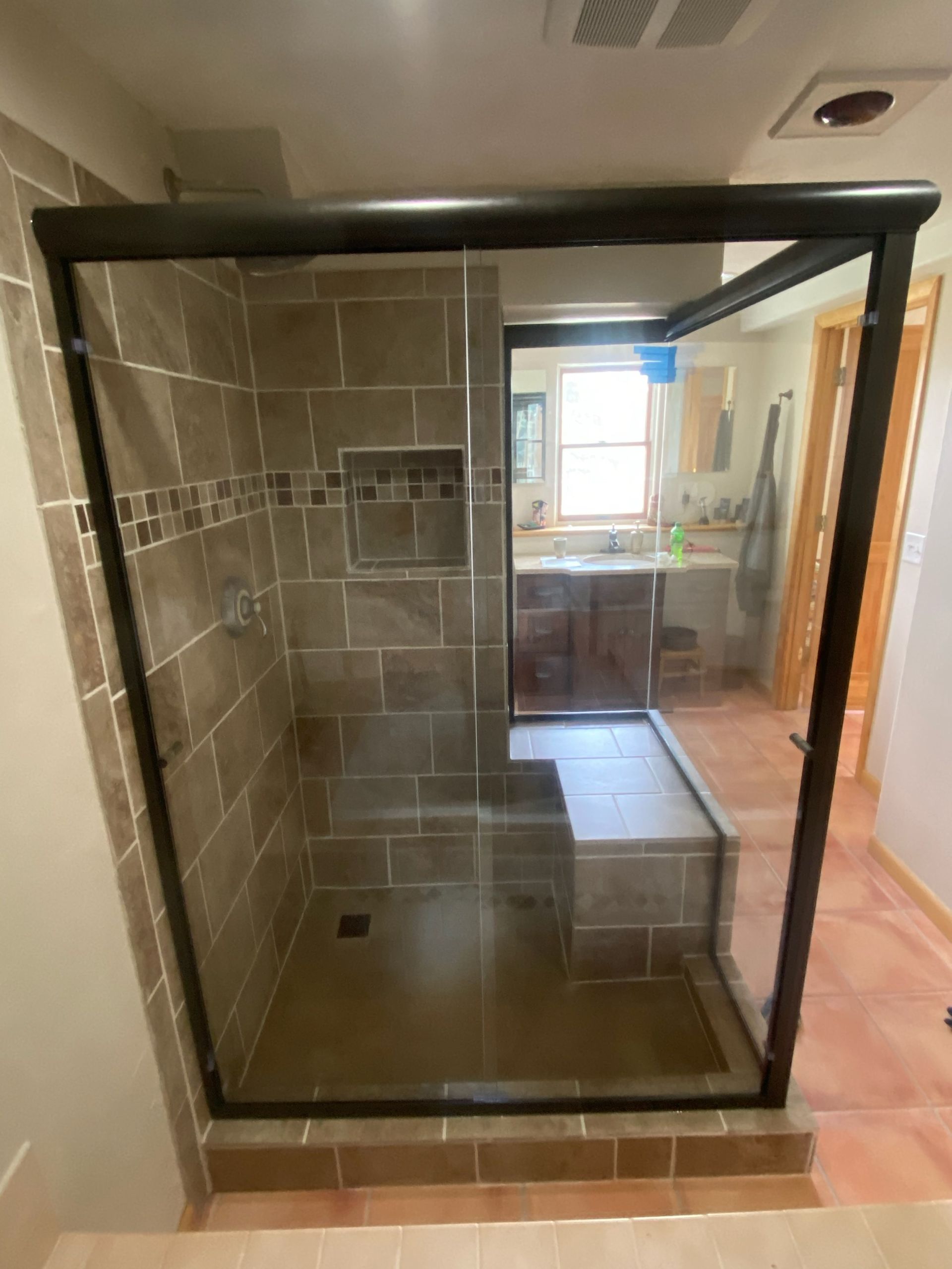 Walk-in shower with black-framed glass enclosure and tiled walls in a bathroom