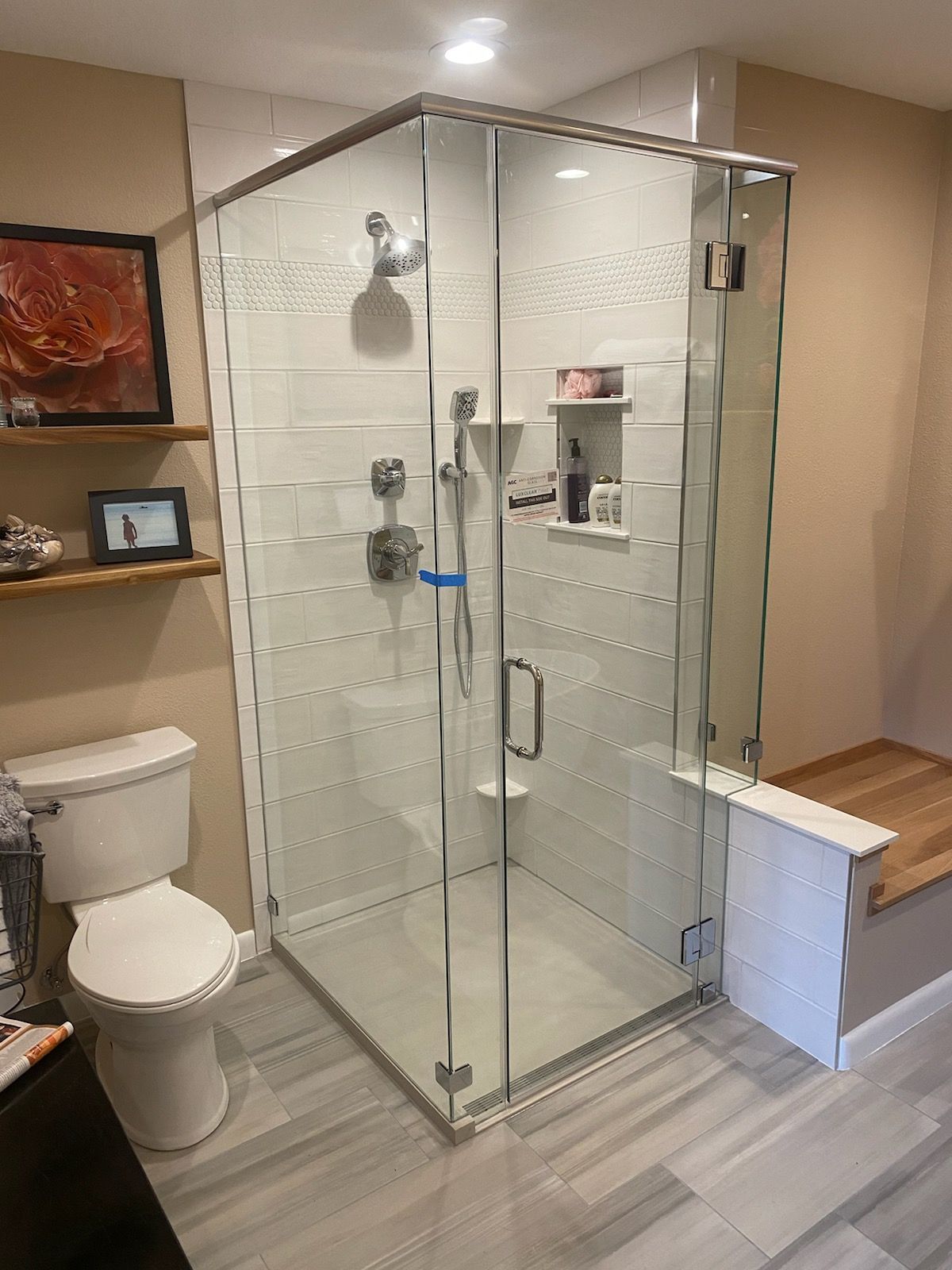 Bathroom with glass-enclosed shower, toilet, shelf, and gray tile floor