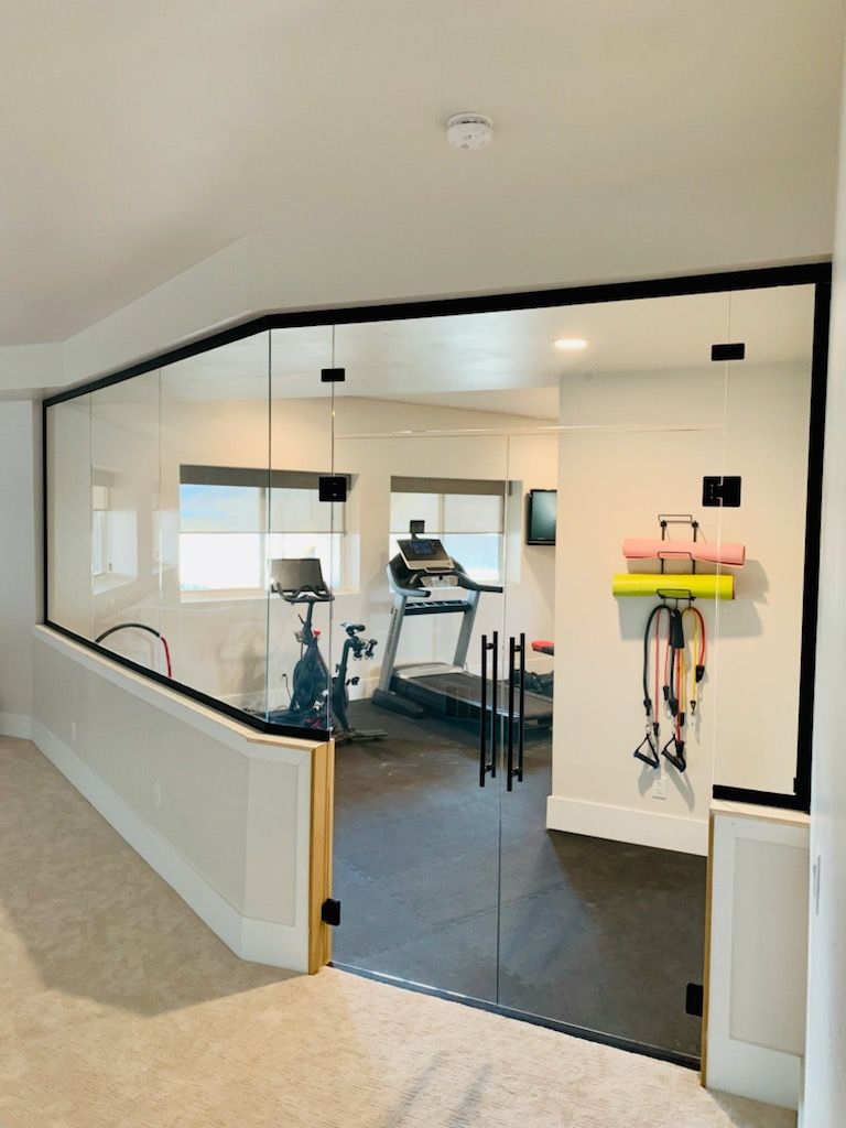 Glass office partition along a hallway, showing a conference room with desk and chairs inside.