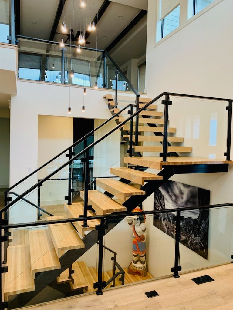 Modern interior with open staircase, black railings, and glass mezzanine in a bright atrium