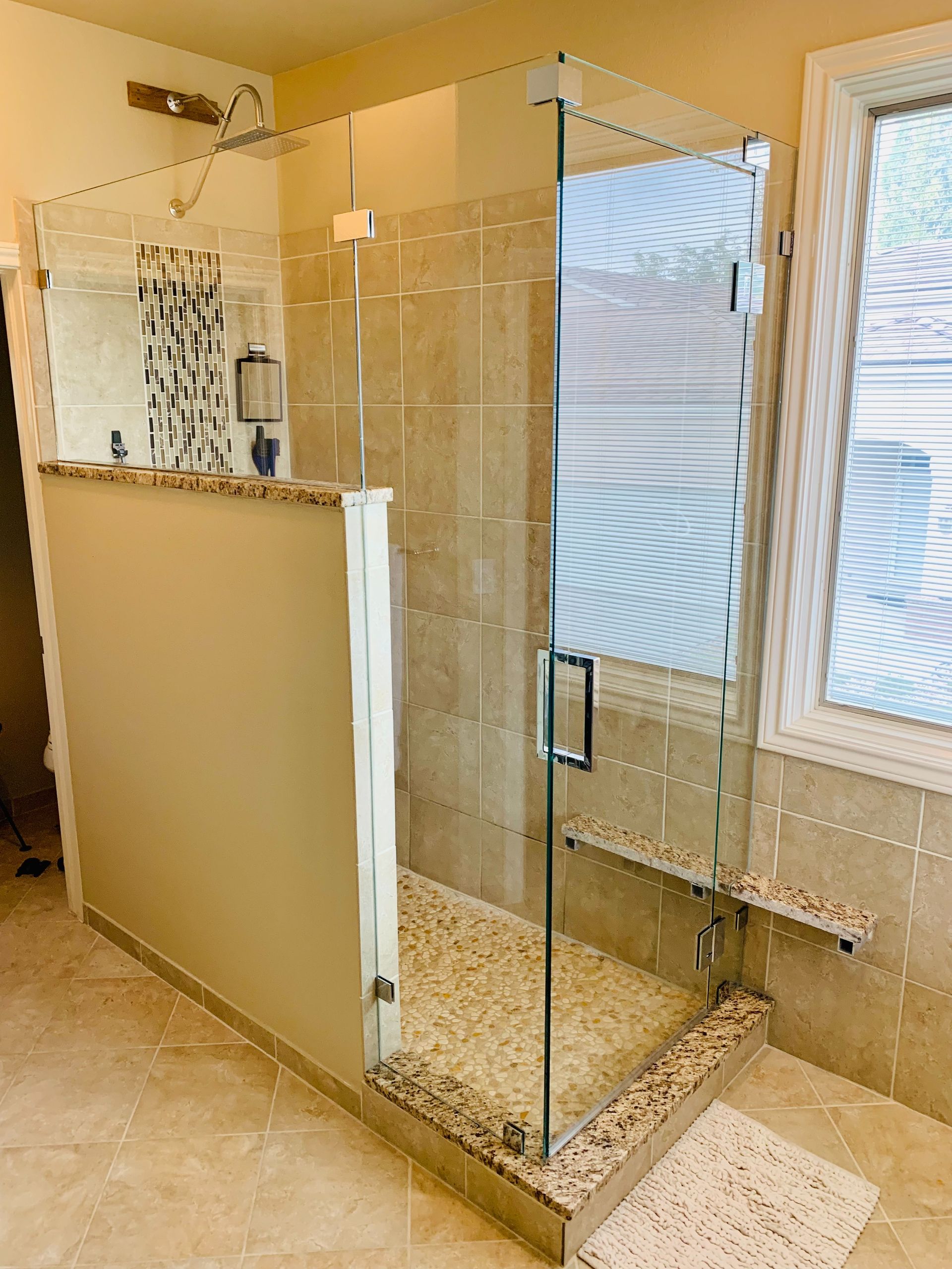 Glass shower enclosure with white privacy partition in a tiled bathroom
