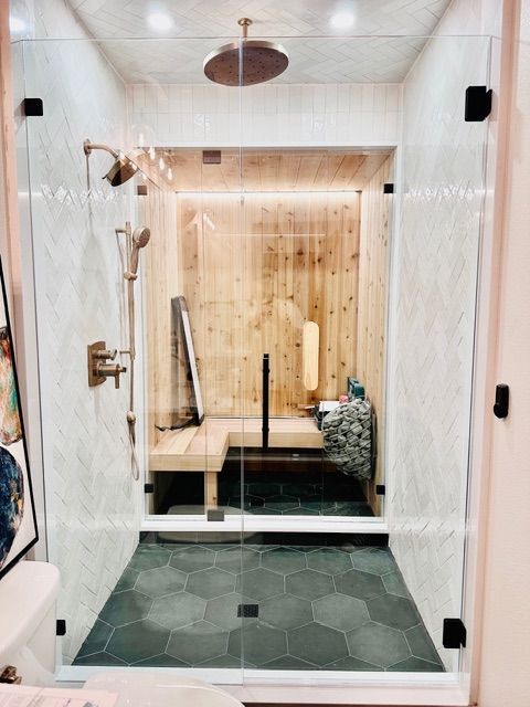 Modern salon interior. Modern bathroom with glass shower, marble walls, hex tile floor, and wooden bench seating area