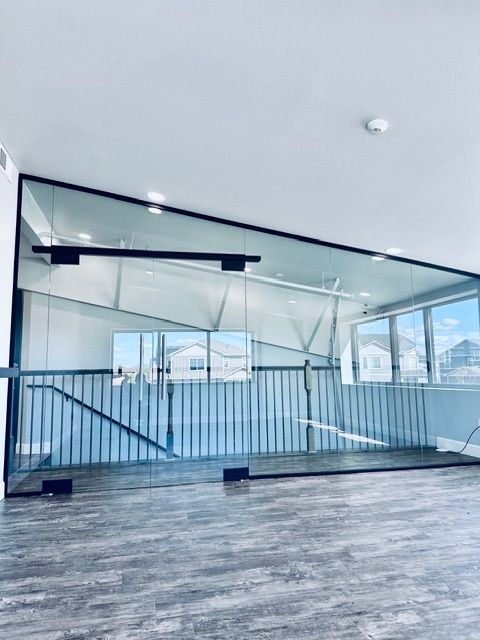 Modern interior with glass railing, gray floor, and large windows overlooking mountains.