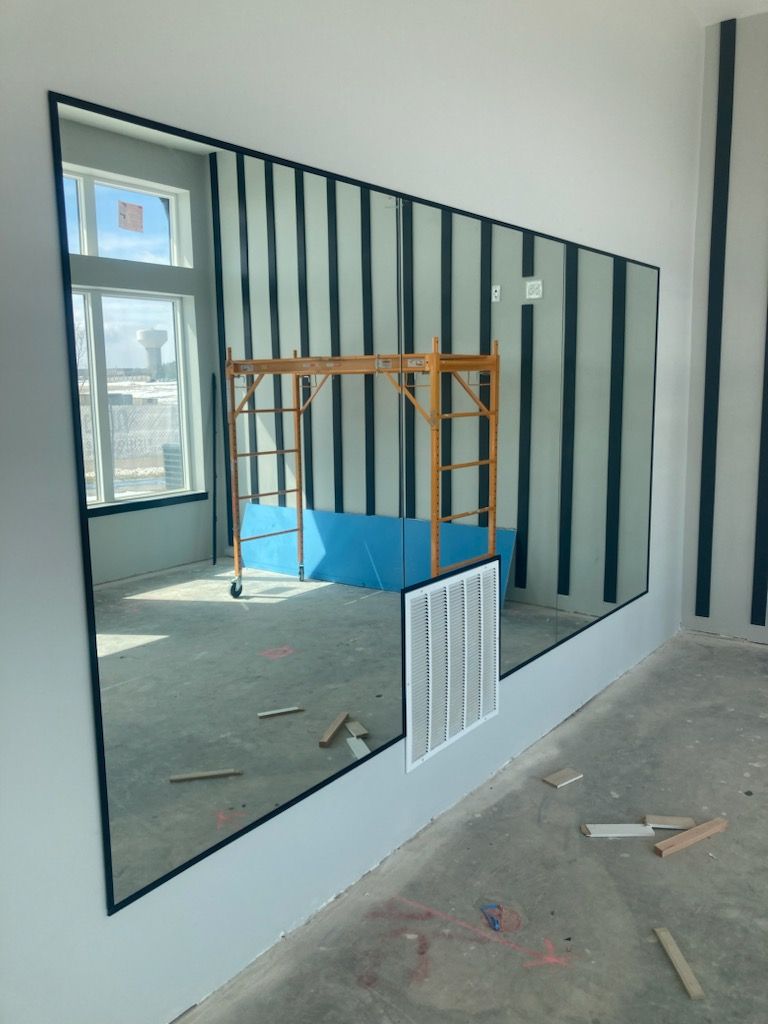 Construction interior with drywall, black framing, blue platform, and a window opening