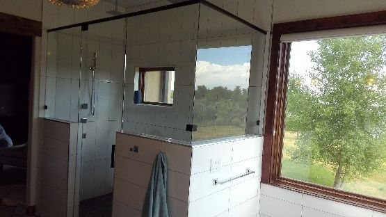 Small room interior with white paneled walls, a window, and a coat hanging on a partition.