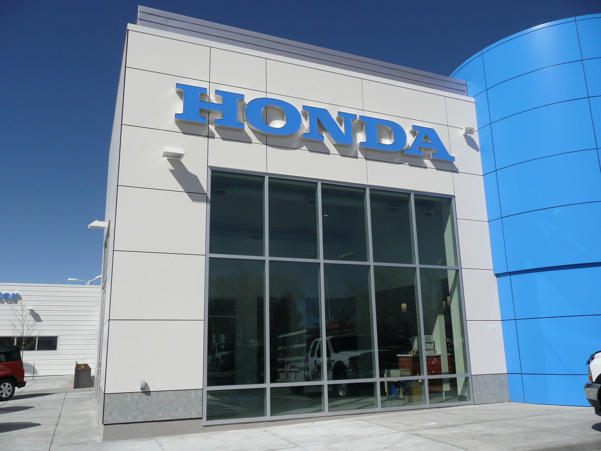 Honda dealership exterior with blue signage and glass entrance under a clear sky