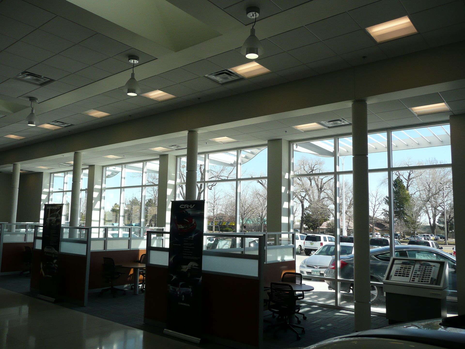 Empty store interior with large front windows and parked cars outside.