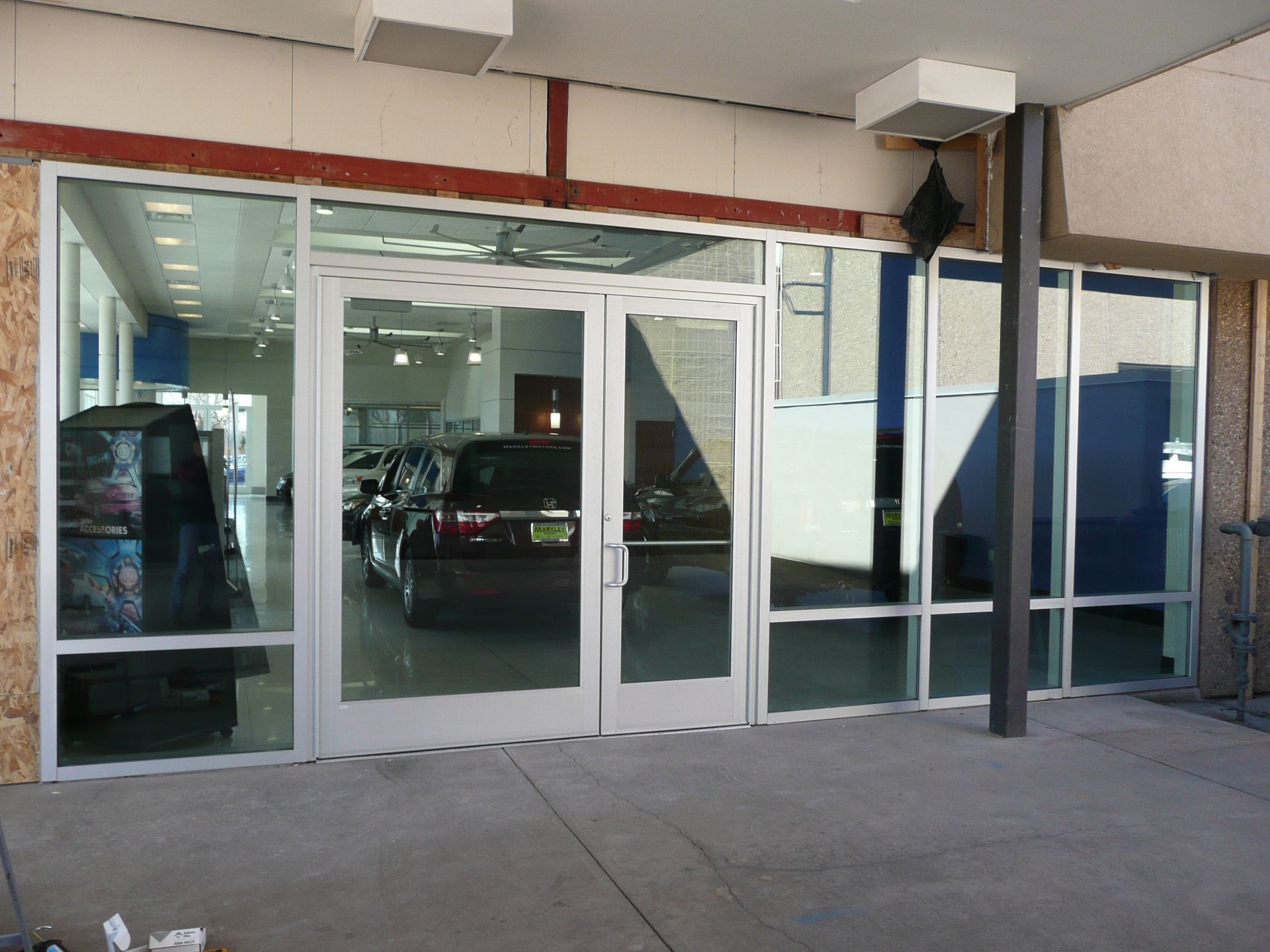 Glass storefront entrance with sliding doors, viewed from a sidewalk under an overhang