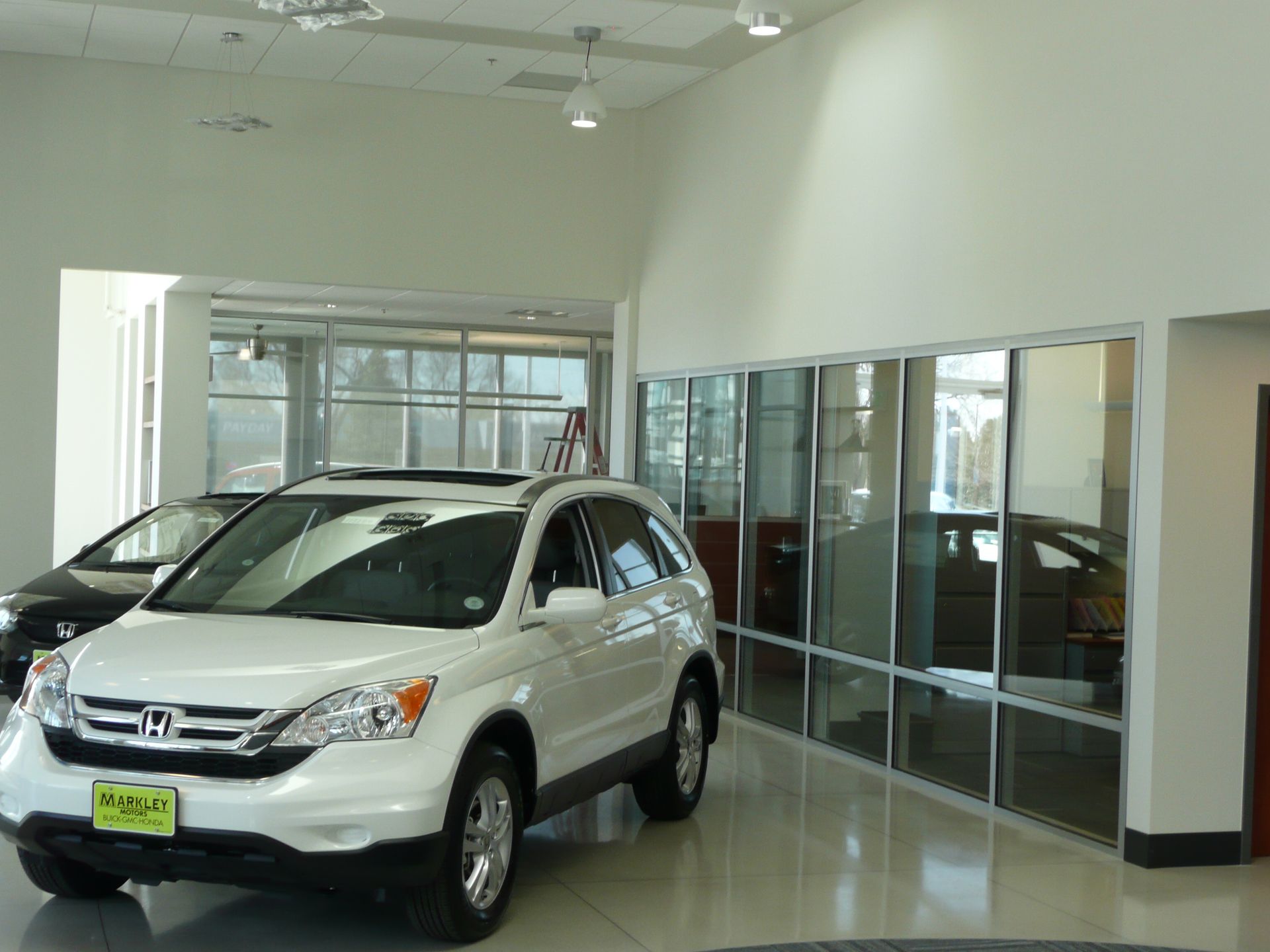 White SUV in a bright car showroom with glass-walled offices and polished floors