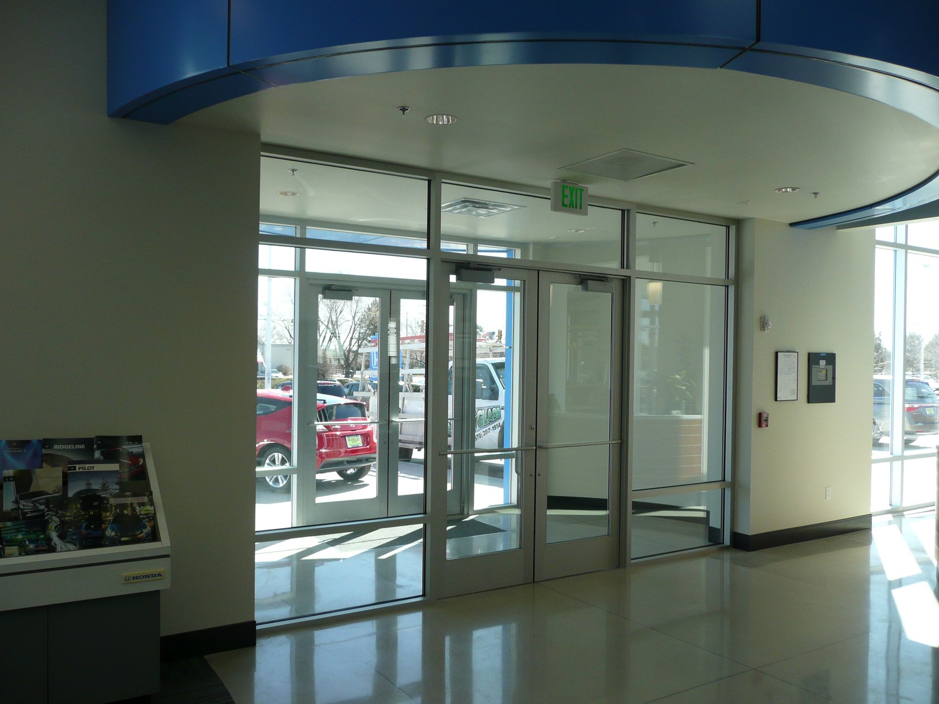 Empty building lobby with glass entrance doors and a curved blue ceiling overhang