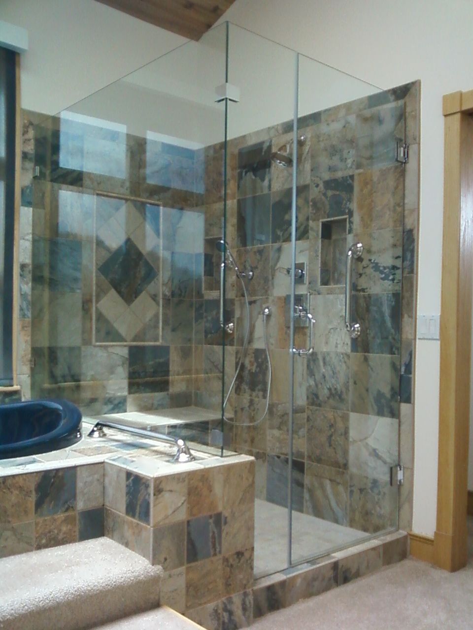Modern bathroom with glass shower enclosure, tiled walls, and a vanity sink.