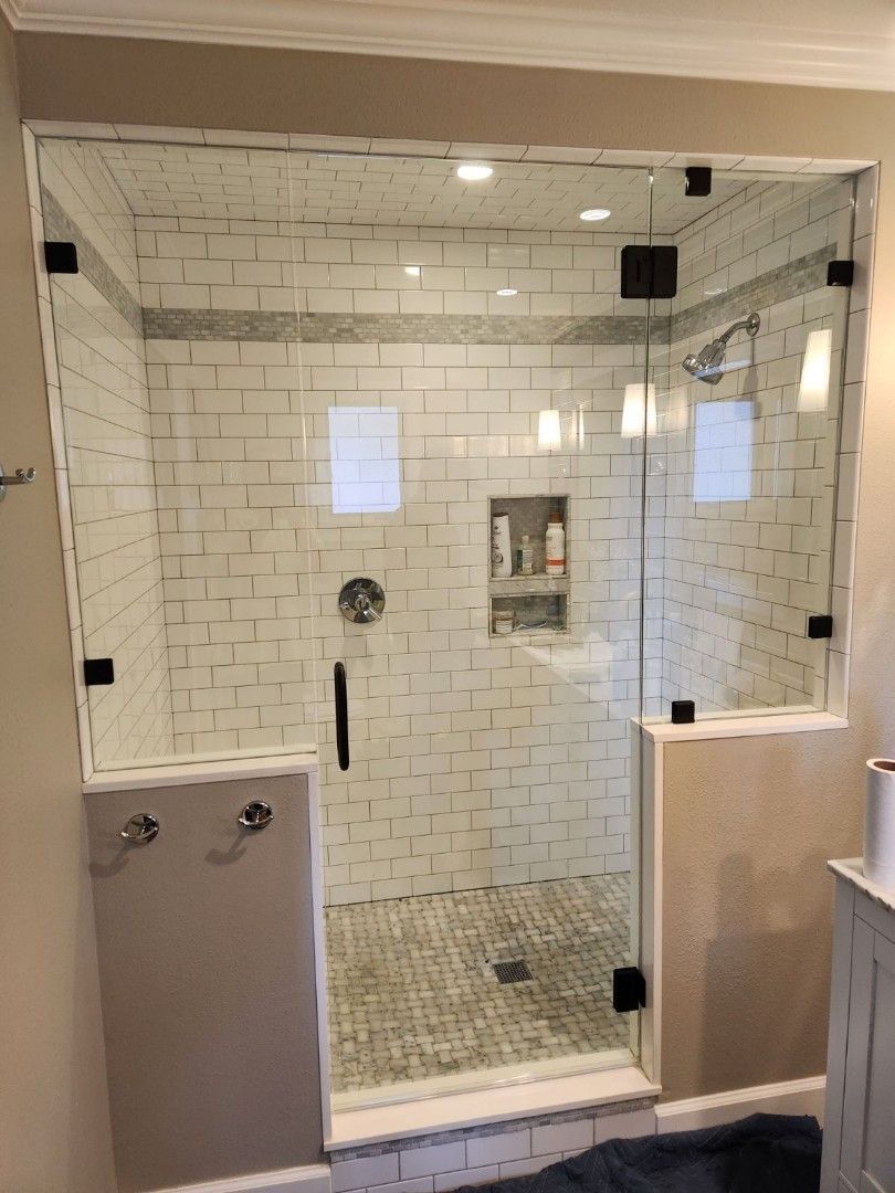 Glass shower stall with white subway tile and a frosted half-wall in a bathroom