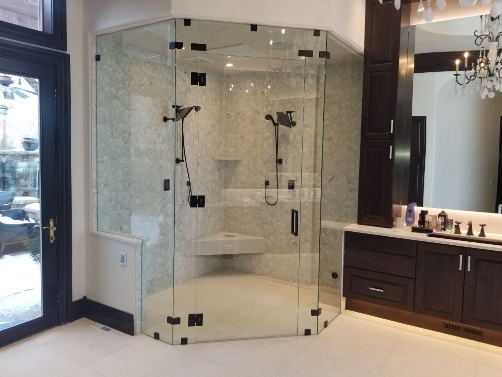 Glass corner shower with tiled walls, dual showerheads, and dark wood vanity in a bathroom
