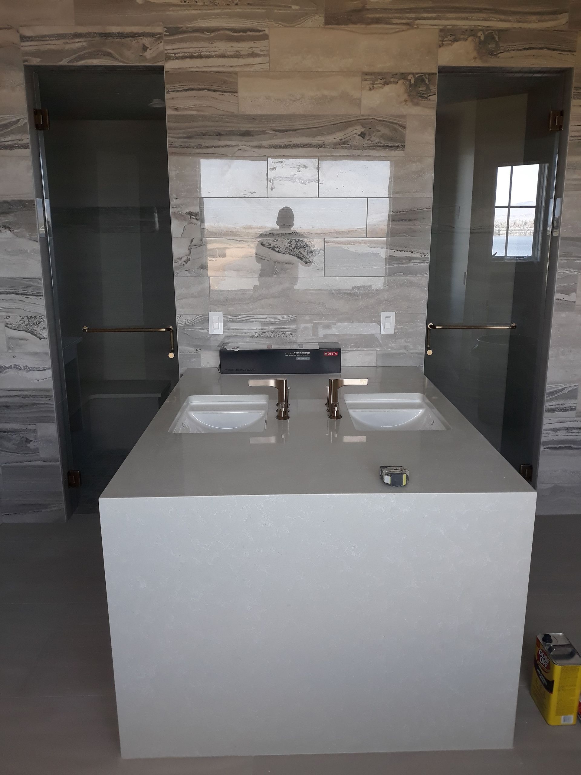 Modern bathroom vanity with two sinks, mirrors, and dark side cabinets against a tiled wall