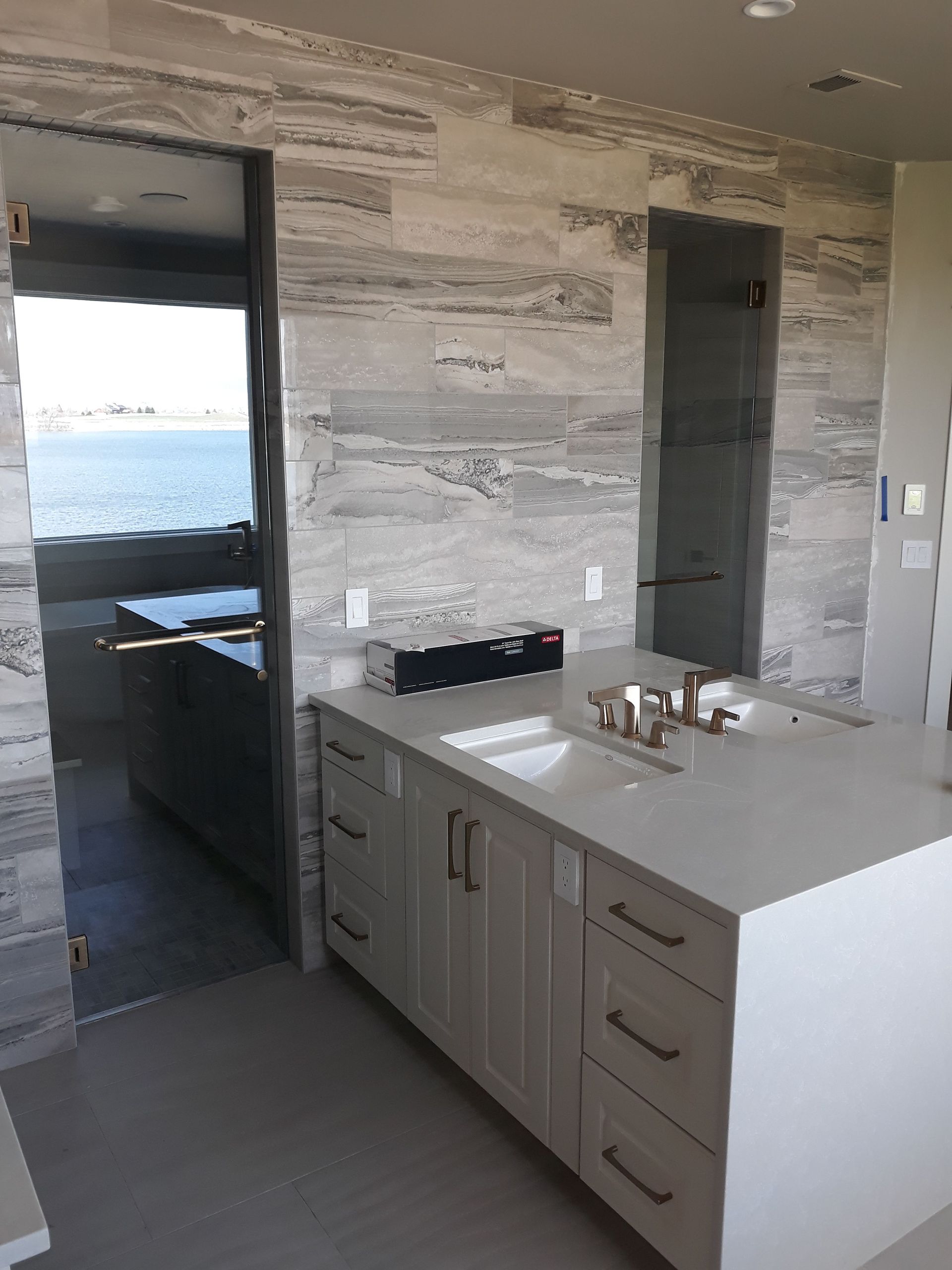 Modern kitchen with gray stone walls, island countertop, and a view to water through the doorway