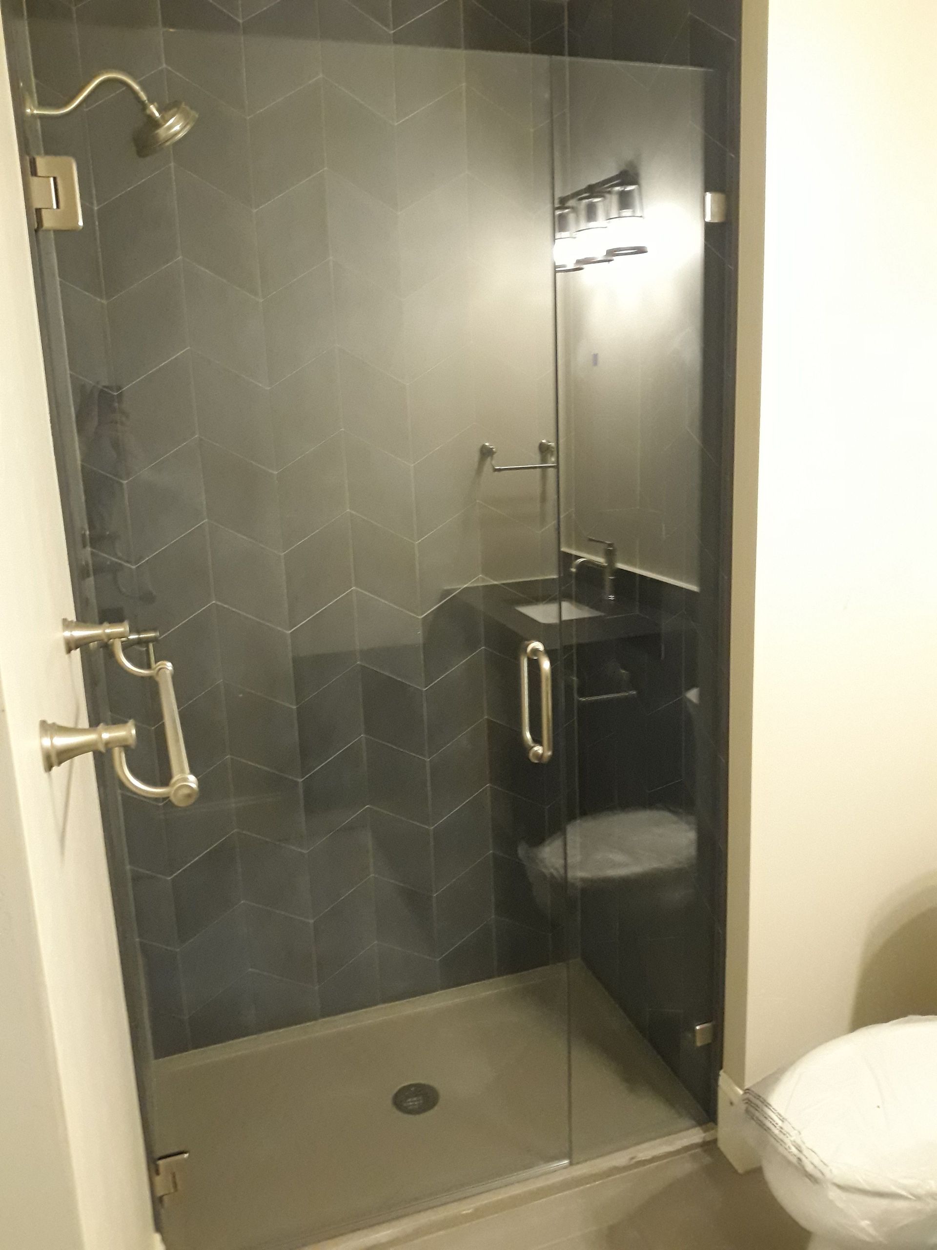 Small tiled glass shower with chrome fixtures and a black vanity in a compact bathroom.