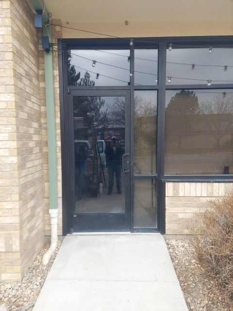 Building entrance with glass door, brick wall, and concrete sidewalk ramp.