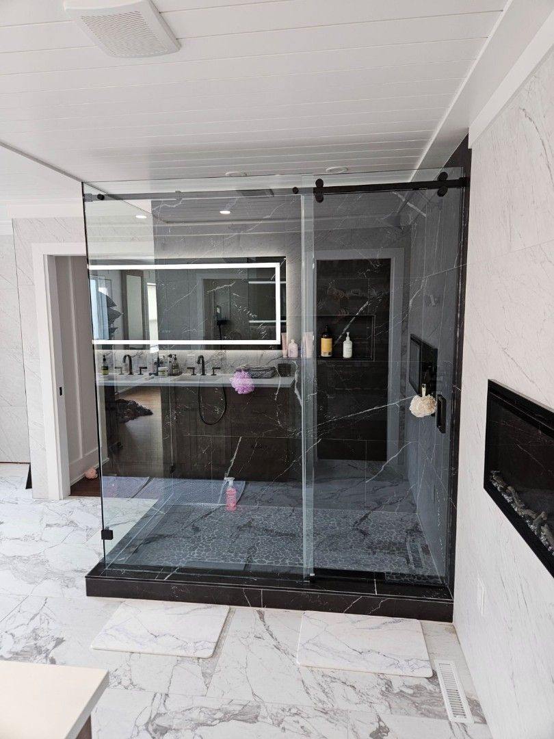 Glass-enclosed indoor patio with marble floor and wall fireplace, viewed from a hallway