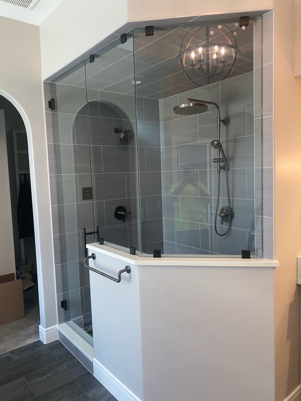 Glass-enclosed tiled shower with rain showerhead and half wall in a modern bathroom
