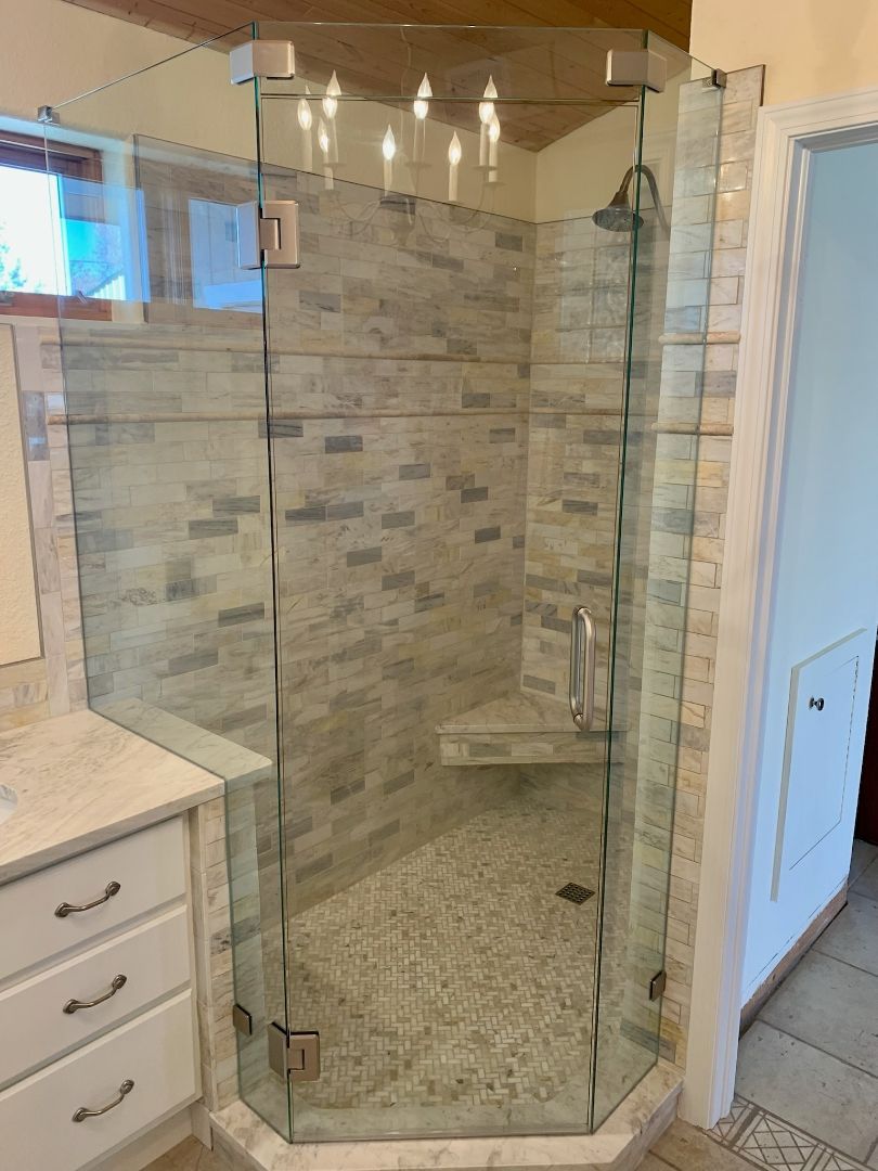Glass shower enclosure with stone tile walls in a bathroom