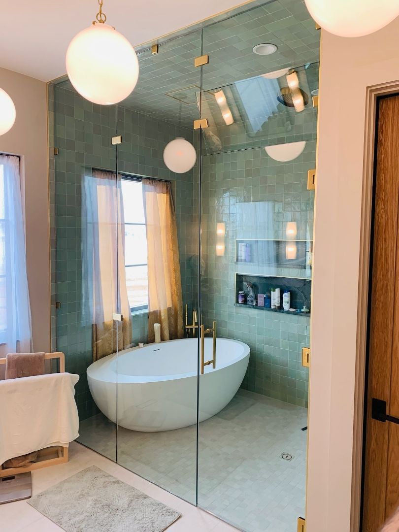 Modern bathroom with freestanding tub, teal tiled walls, and pendant globe lights