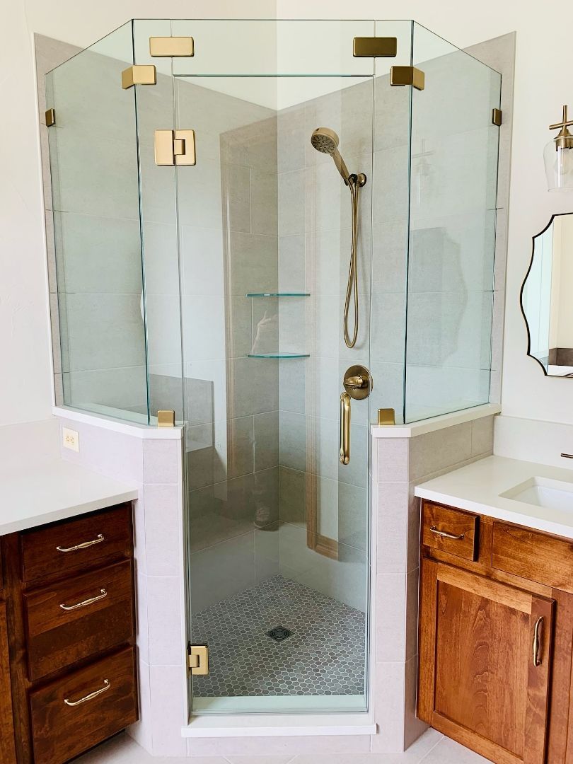 Glass walk-in shower with chrome fixtures, white tile floor, and wooden vanity cabinets on both sides