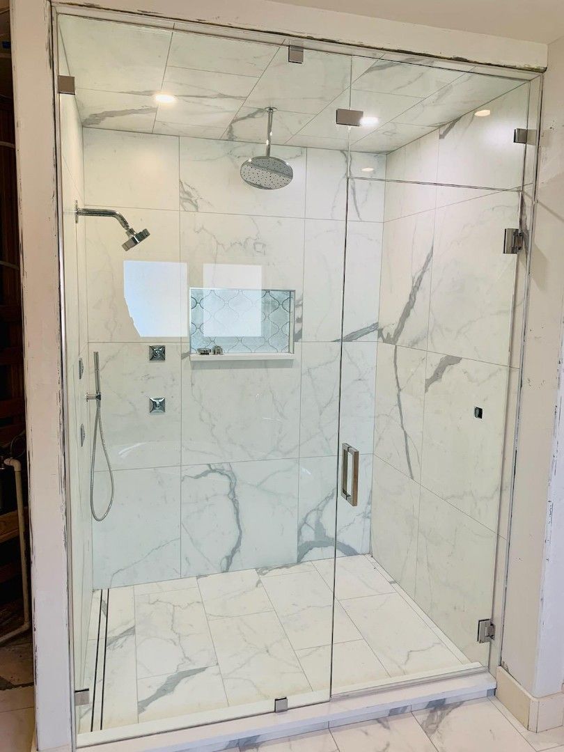 Modern walk-in shower with glass enclosure and marble-pattern tile walls and floor