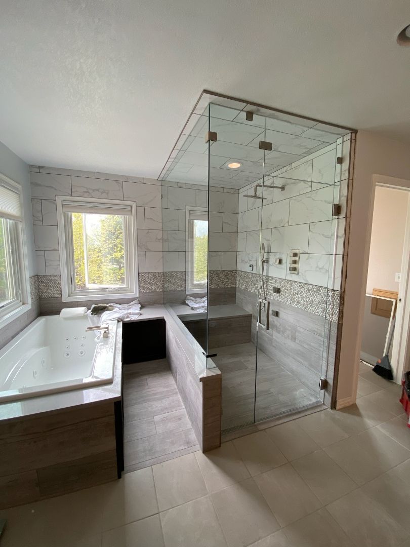 Modern bathroom with glass shower, white vanity, and large window света