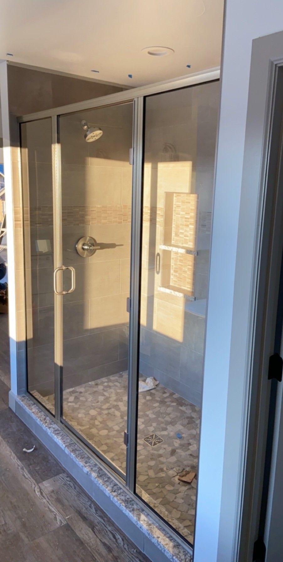 Glass shower enclosure in a tiled bathroom with a sliding door and chrome handle