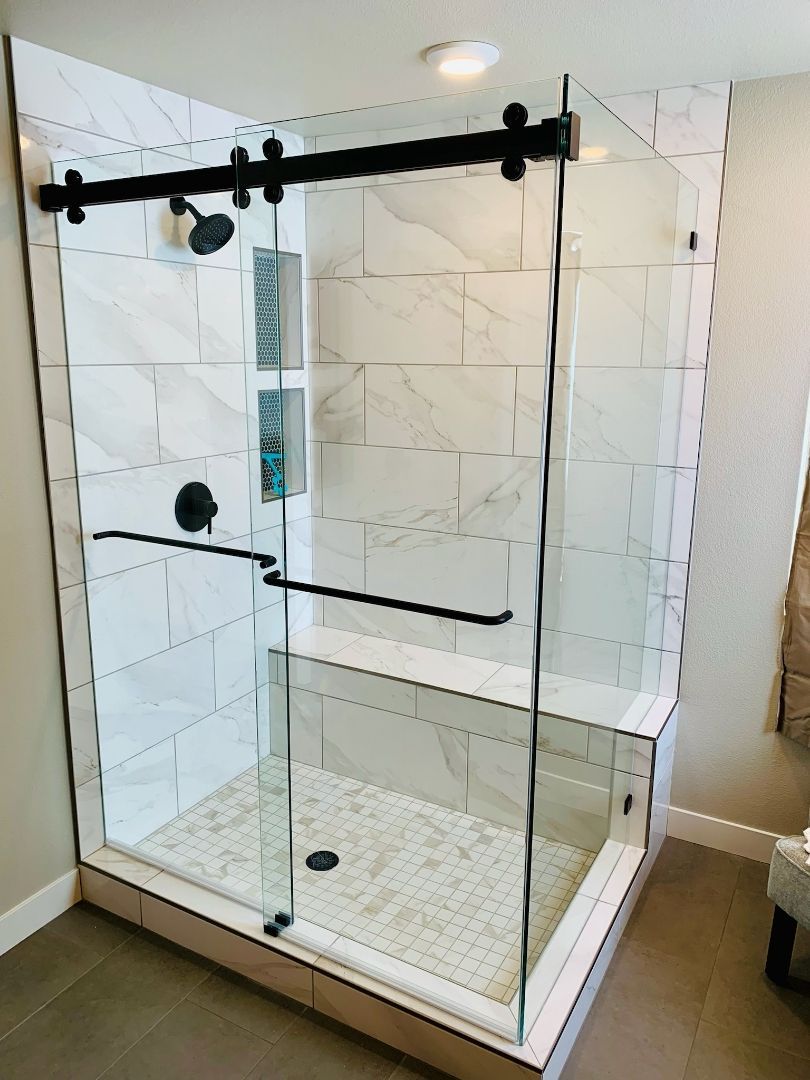Glass shower enclosure with black hardware and white tiled interior in a bathroom