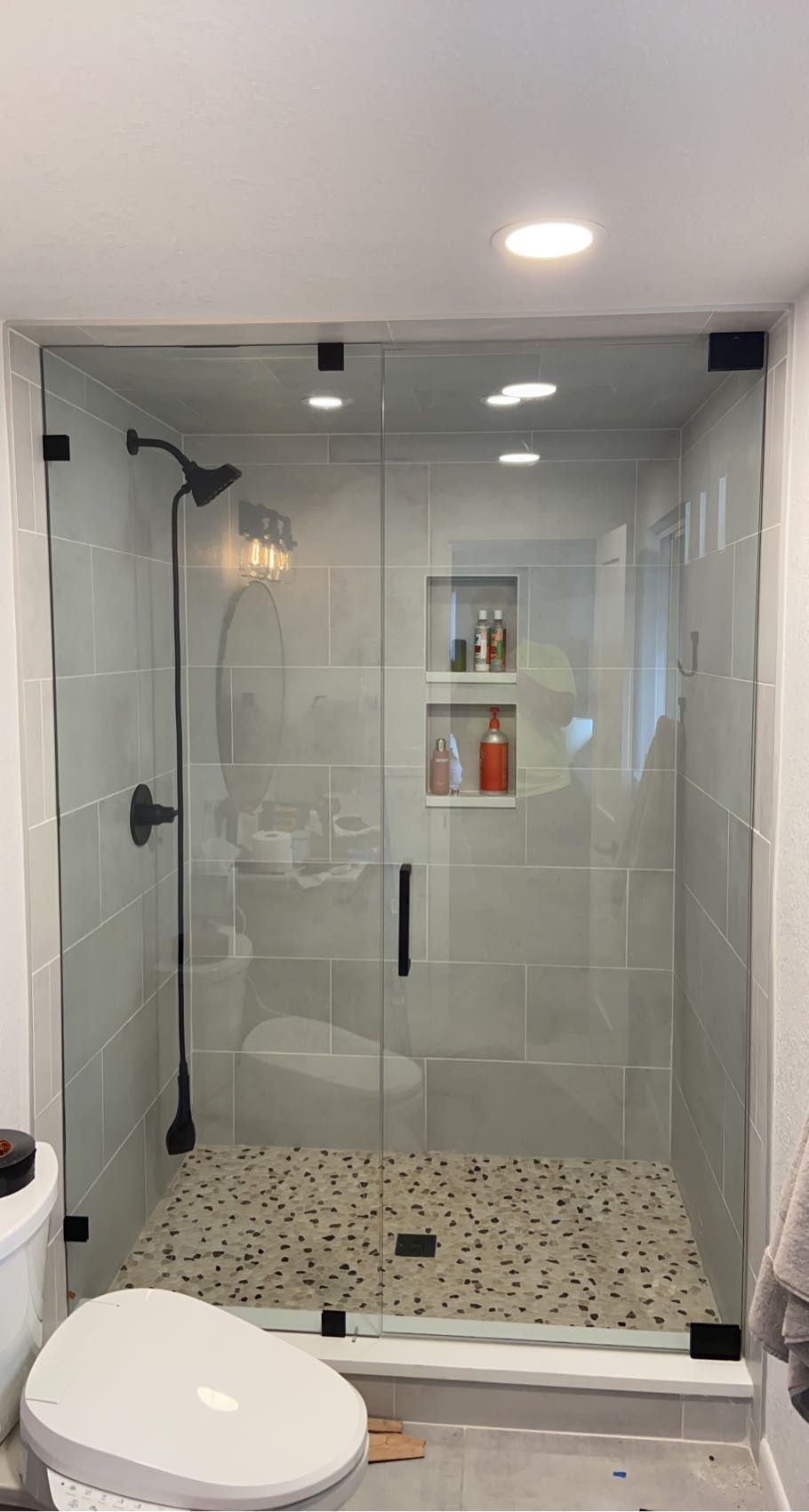 Modern bathroom shower with glass door, tiled walls, and a white toilet in the foreground