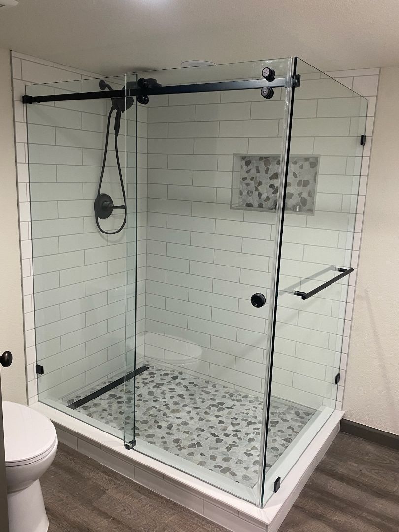 Glass walk-in shower with white tile, mosaic floor, and chrome fixtures.