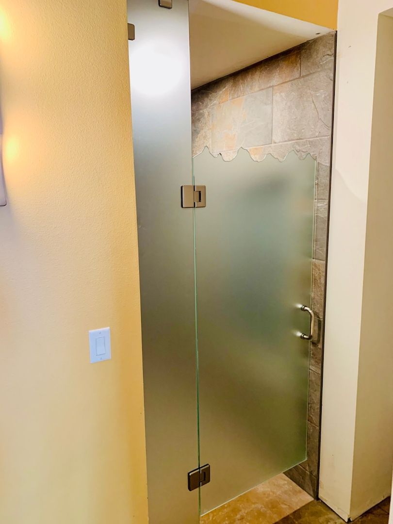 Frosted glass shower door in a bathroom with beige walls and tile flooring