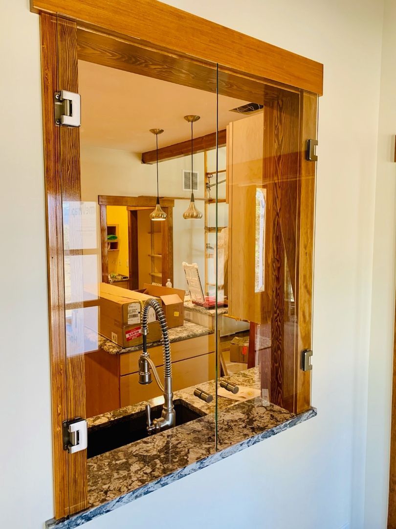 Wooden-framed pass-through window with glass panes overlooking a bathroom with a sink and mirror