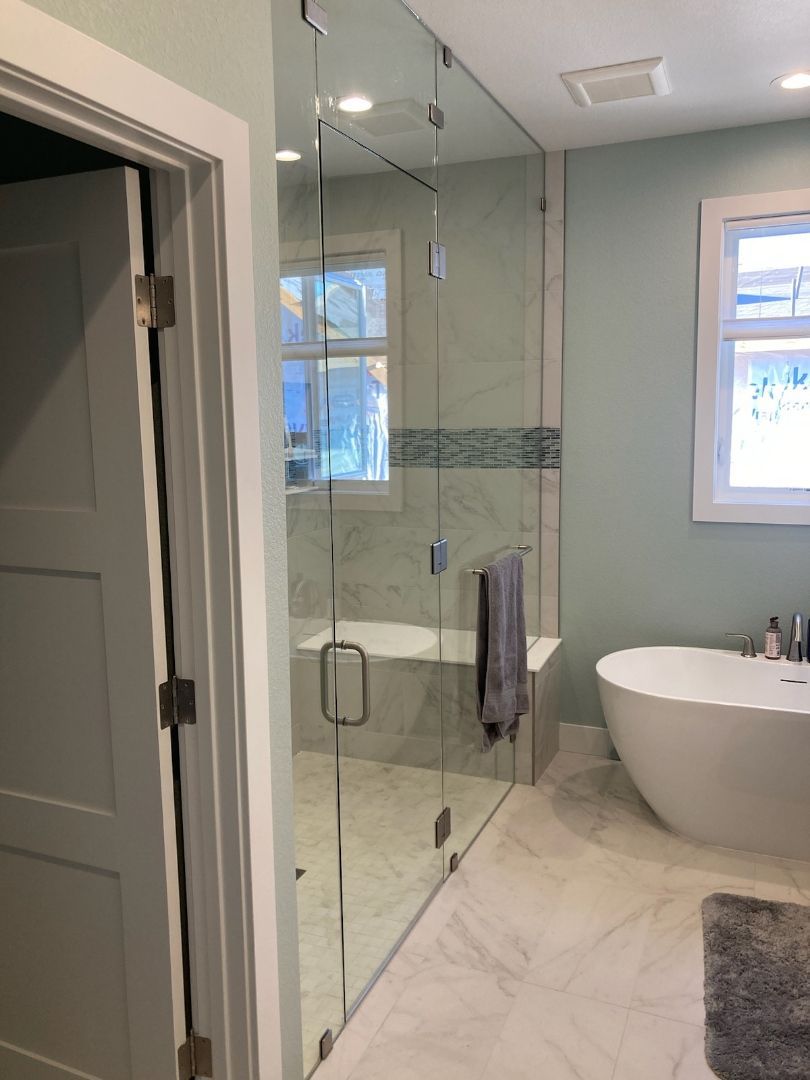 Modern bathroom with glass shower, freestanding tub, and marble tile flooring