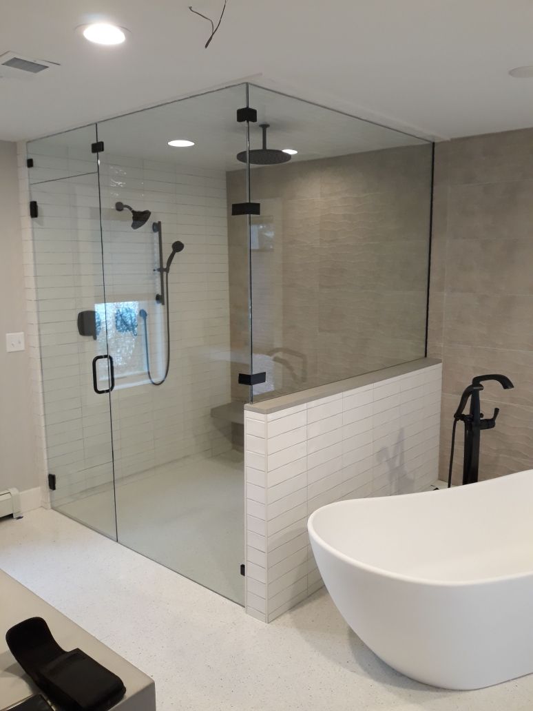 Modern bathroom with glass shower, white tub, and round sink on a tiled counter