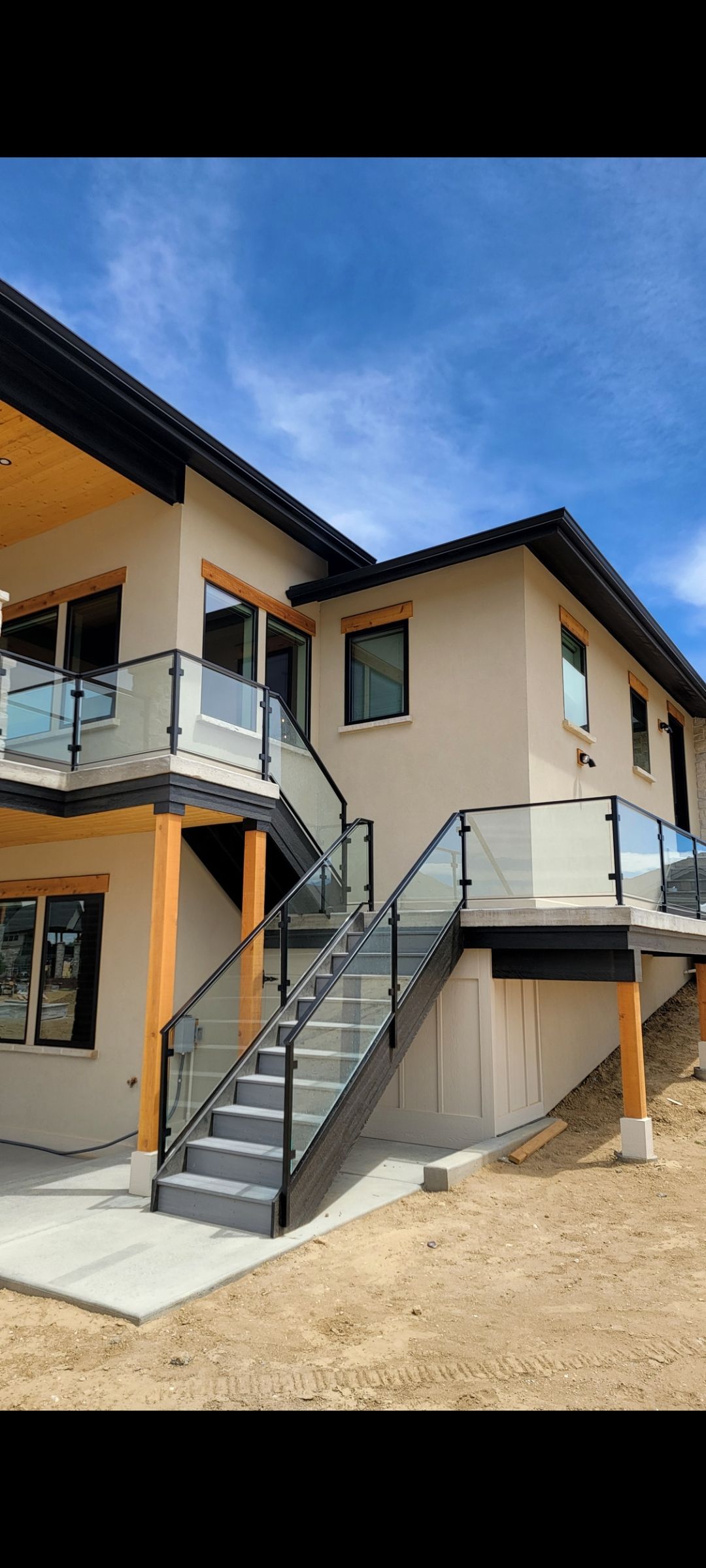 Modern two-story house with beige walls, orange trim, and an exterior metal staircase under a blue sky