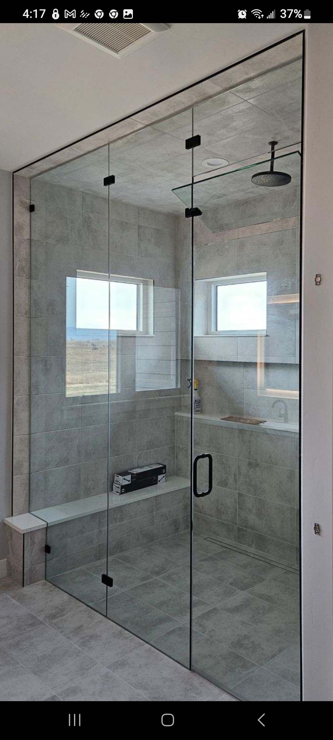 Glass shower enclosure in a tiled bathroom with chrome handle and fixtures, shown from outside.