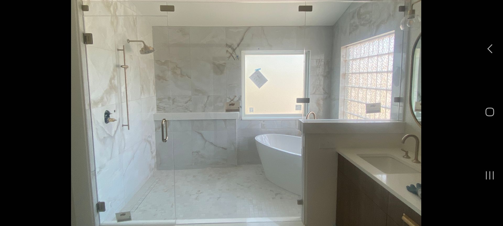 Bright white modern bathroom with a freestanding tub, walk-in shower, and vanity by the window.