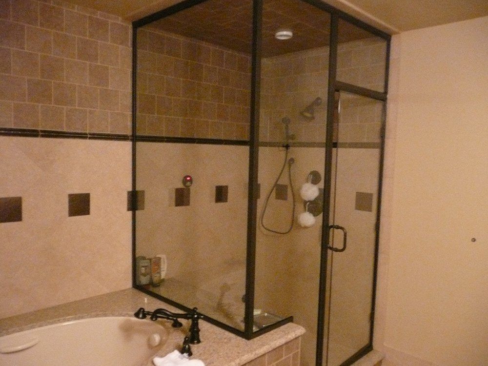 Corner bathroom with beige tile, glass shower enclosure, and white sink faucet.