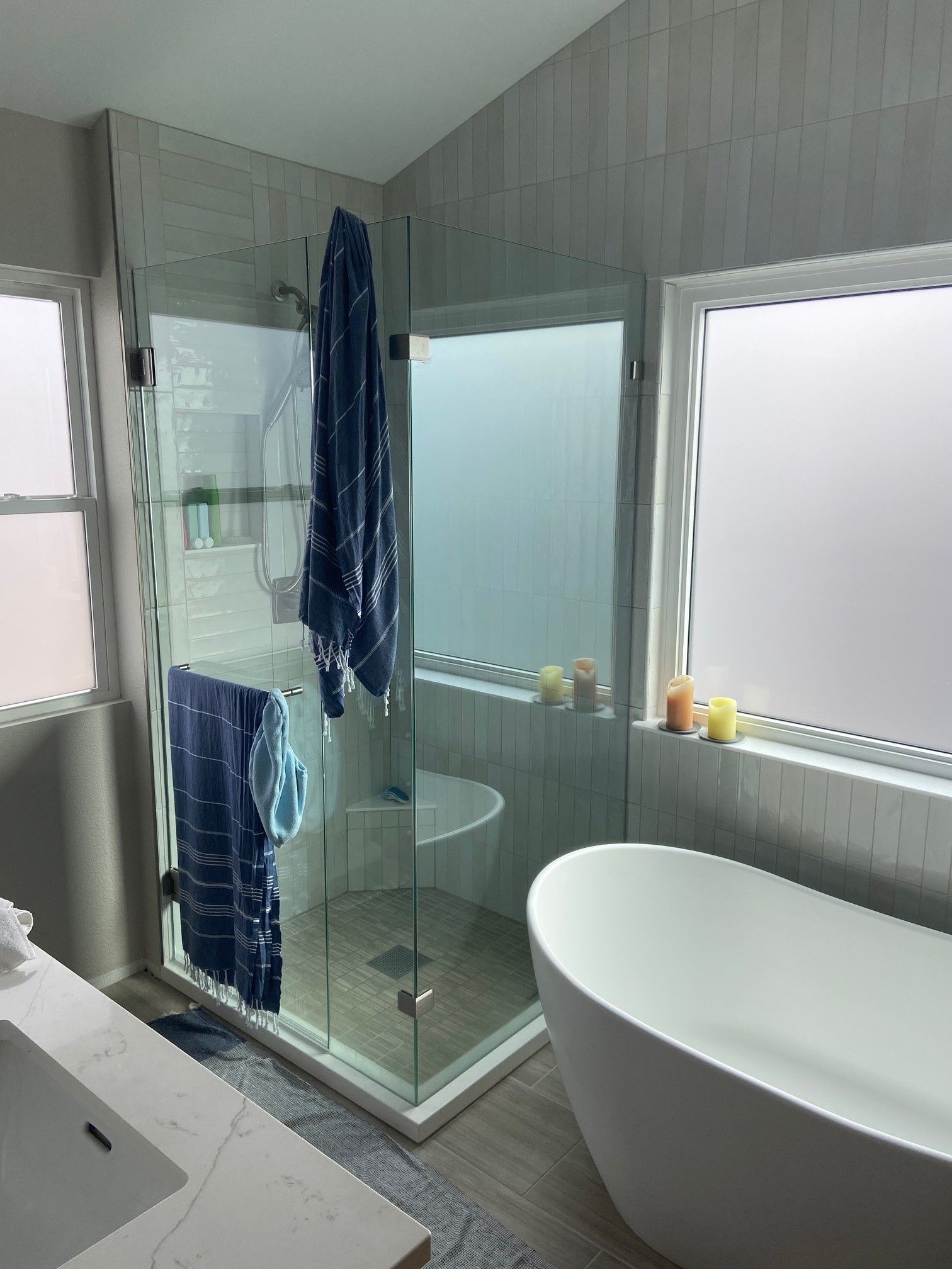 Modern bathroom with glass shower, freestanding tub, and towels hanging on the shower door