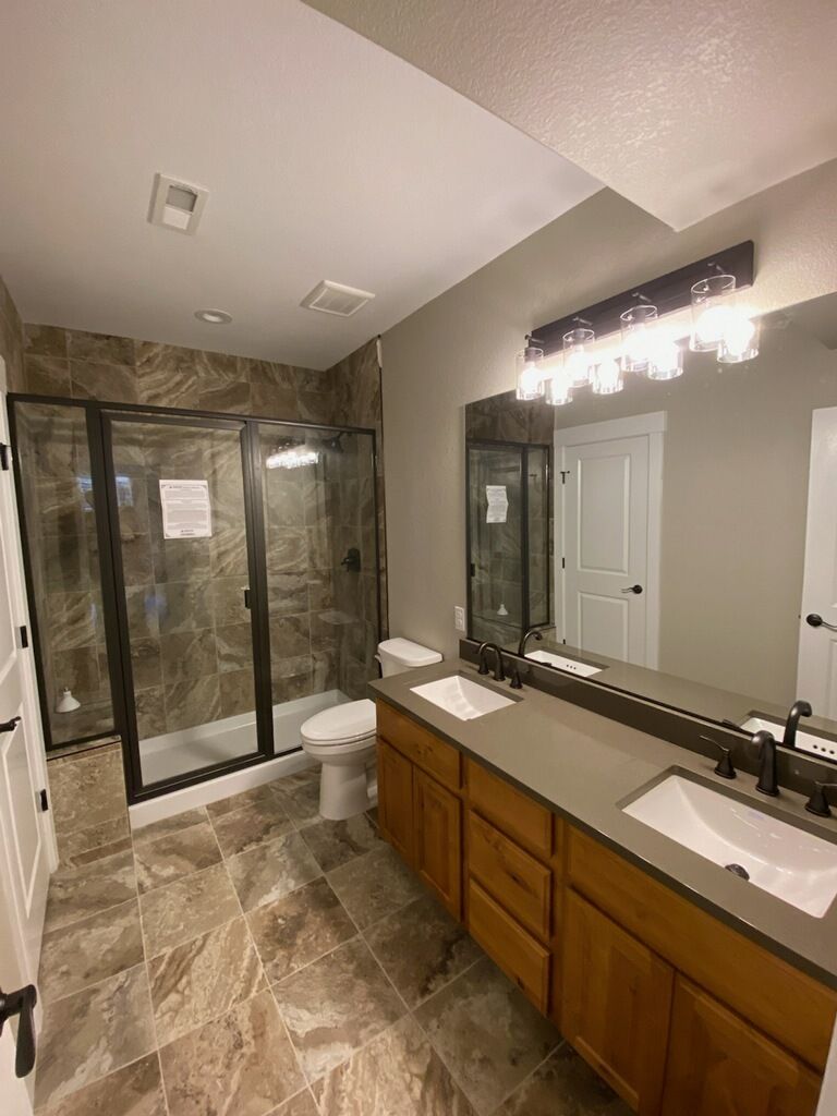 Modern bathroom with glass shower, double vanity, and tiled floors