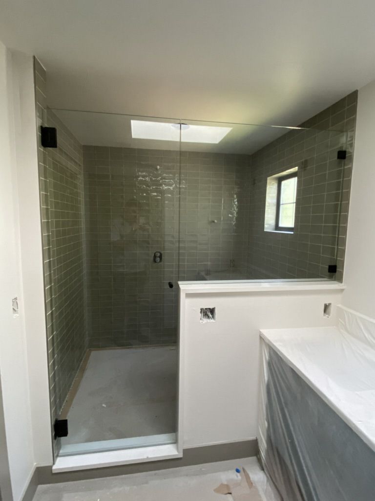 Modern tiled bathroom with glass shower, skylight, and window beside a vanity countertop