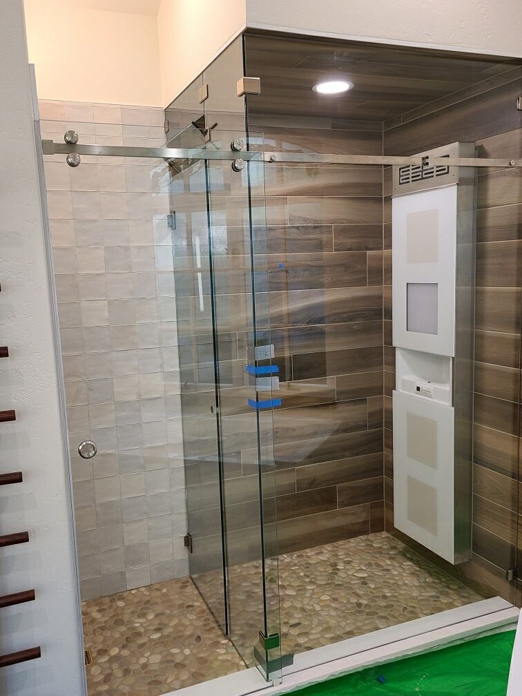 Glass shower enclosure with wood-look tile walls and stone mosaic floor in a modern bathroom